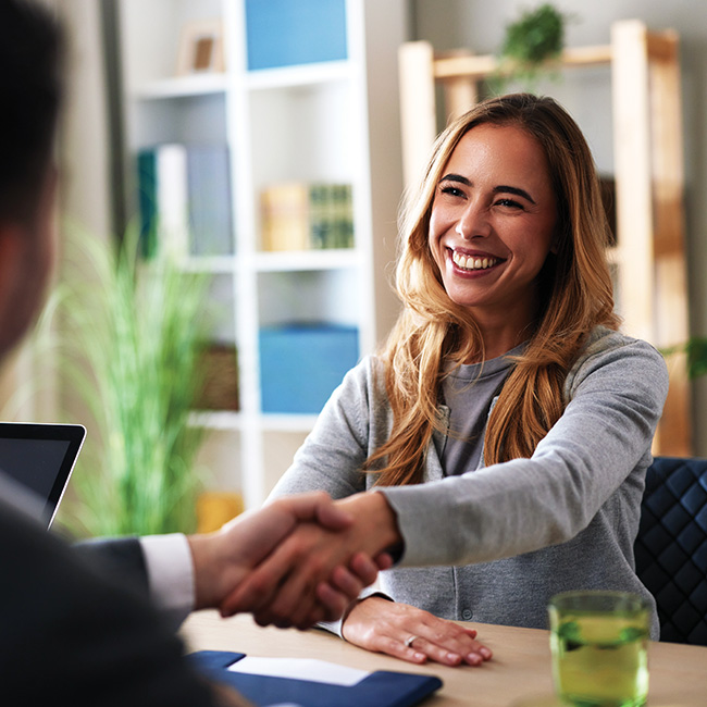 Woman shaking hands with someone sitting across from her