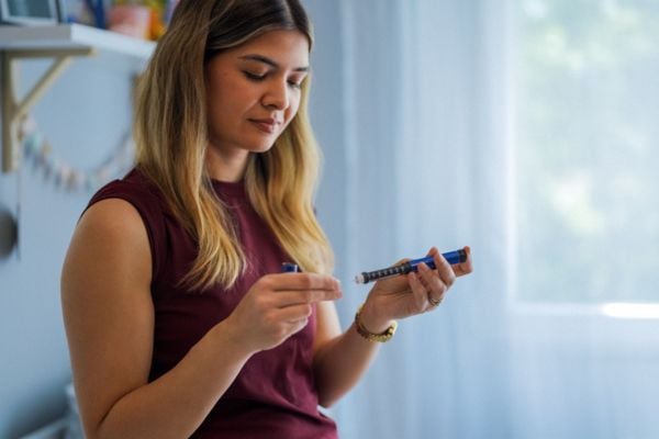 Woman prepares to take a GLP-1 injection.