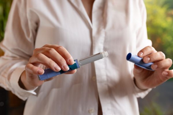 Woman holding GLP-1 injection pen.